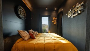 Une chambre avec un grand lit, un élément de décoration circulaire sur le mur et une vue à travers la porte.