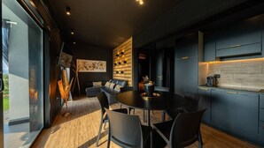 Une cuisine moderne avec des meubles de rangement sombres, une table de salle à manger ronde et des chaises noires.