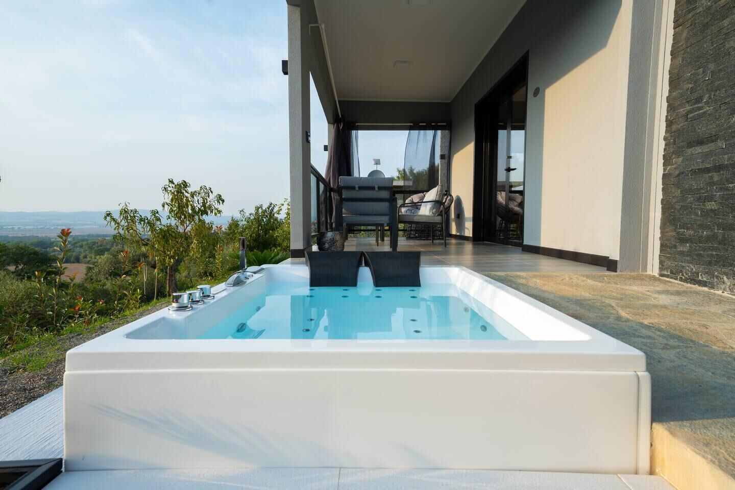 Un bain à remous extérieur moderne offrant une vue sur la campagne.