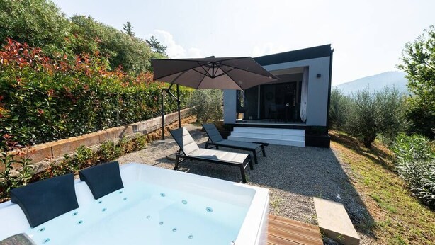 A modern outdoor hot tub area with lounge chairs and a pergola umbrella. - One-room Apartment "Suite Love" with View (SCARLINO)