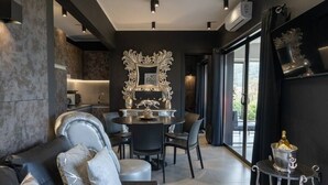 A modern dining area with a round table, chairs, and a decorative mirror. - Passion Suite with Garden and Whirlpool (SCARLINO)