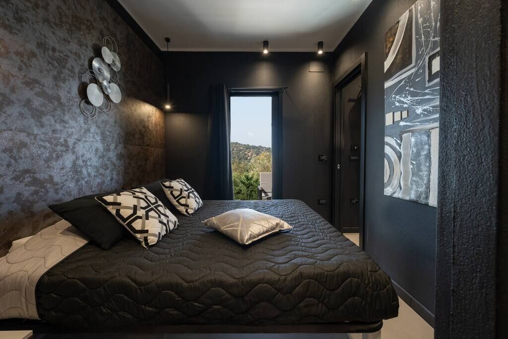 Une chambre moderne avec un grand lit, un luminaire fixé au mur et une vue par la fenêtre.