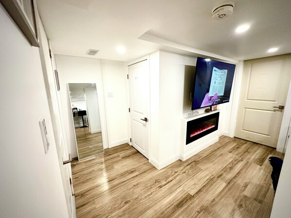 Un salon moderne avec un téléviseur à écran plat fixé au mur, une cheminée et un plancher en bois.