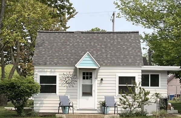 A single-story house with a gabled roof, a front door, and two windows with shutters. - Lakeview Cottage, Walk to the beach, parks & downtown. Early booking discount! (Ludington)