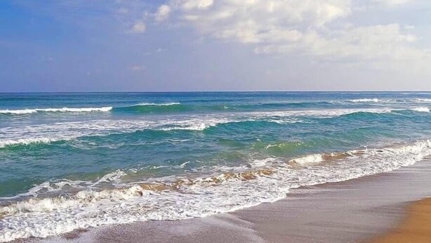 Una platja amb onades i un cel clar.