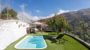 A swimming pool with artificial grass, lounge chairs, and a view of a mountainous landscape. - Casa Abuela - House in the countryside with pool (Vega de San Mateo)