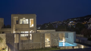 A modern multi-story building with a swimming pool, stone facade, and multiple balconies. - Villa Thoe by Thines Villas (Lefkada)