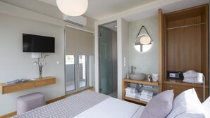 A modern hotel room with a large bed, a television, a bathroom with a mirror, and a wardrobe. - Villa Thoe by Thines Villas (Lefkada)