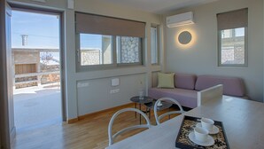A modern room with a sofa, a dining table with chairs, and a small round table with a vase. - Villa Thoe by Thines Villas (Lefkada)
