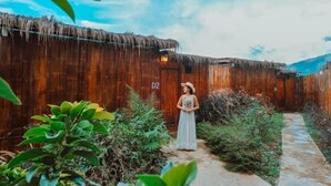 A rustic wooden structure with a thatched roof, a pathway, and lush greenery. - MonLomNao Homestay (Mae Rim)
