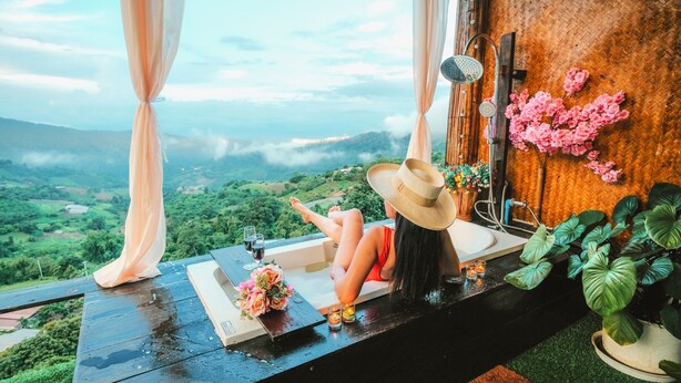 A woman relaxing in a bathtub with a scenic view of a valley. - MonLomNao Homestay (Mae Rim)