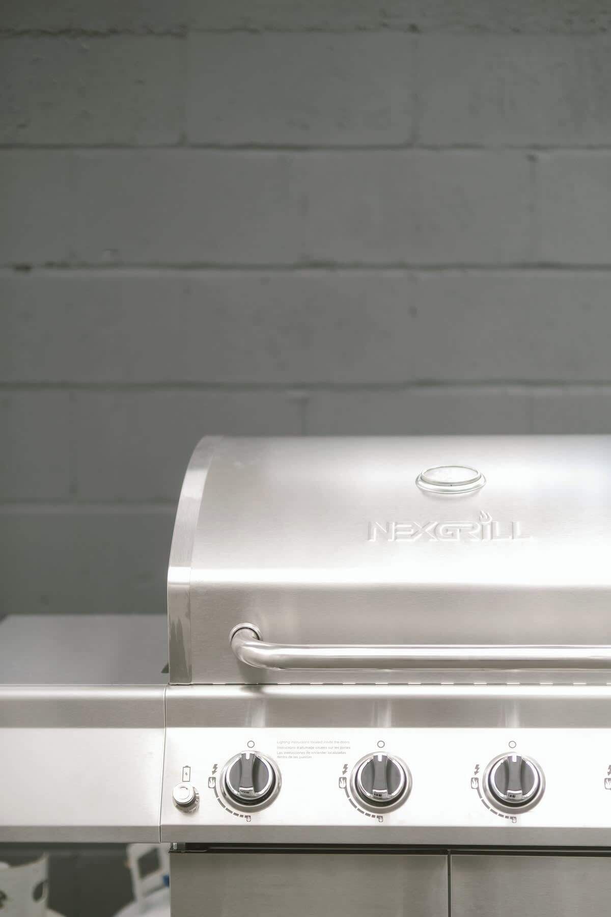 Ein Grill von NexGrill aus Edelstahl mit drei Drehreglern und einem Griff.