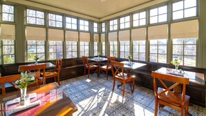 A sunlit room with large windows, wooden furniture, and a tiled floor. - The Lafayette Inn (Easton)