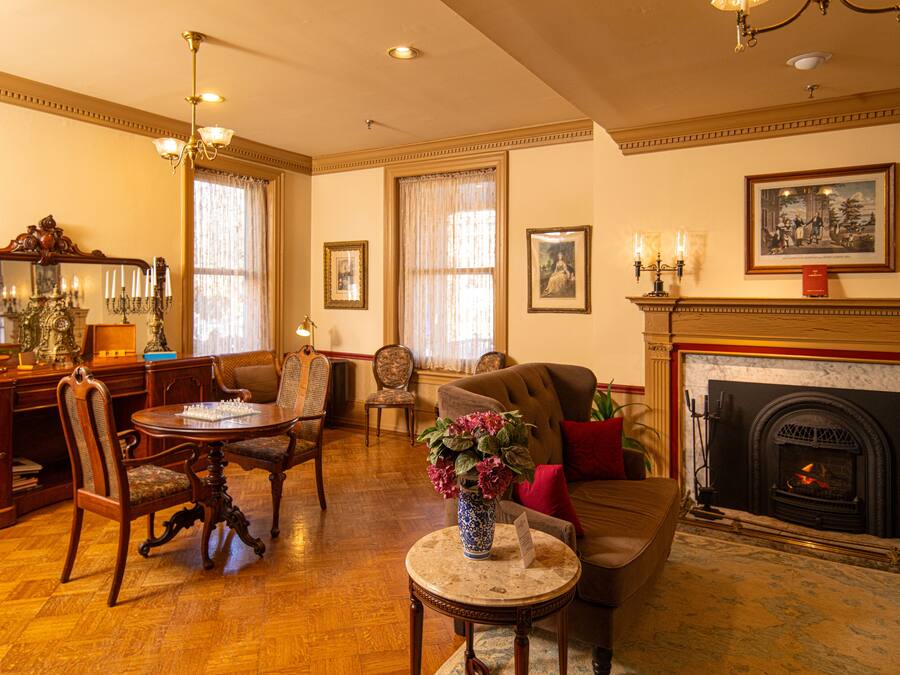 A traditional living room with a fireplace, wooden furniture, and a chandelier.