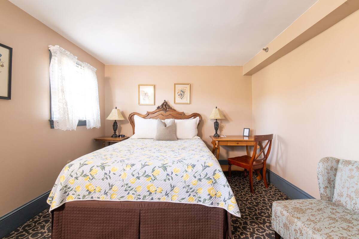 A hotel room with a bed, a desk, a chair, and a small sofa.