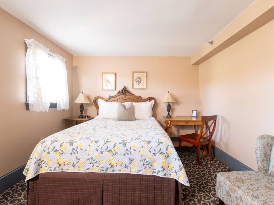 A hotel room with a bed, a desk, a chair, and a small sofa.