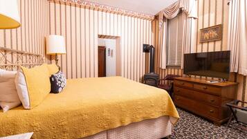 A hotel room with a large bed, a dresser, a television, and a door leading to another room.