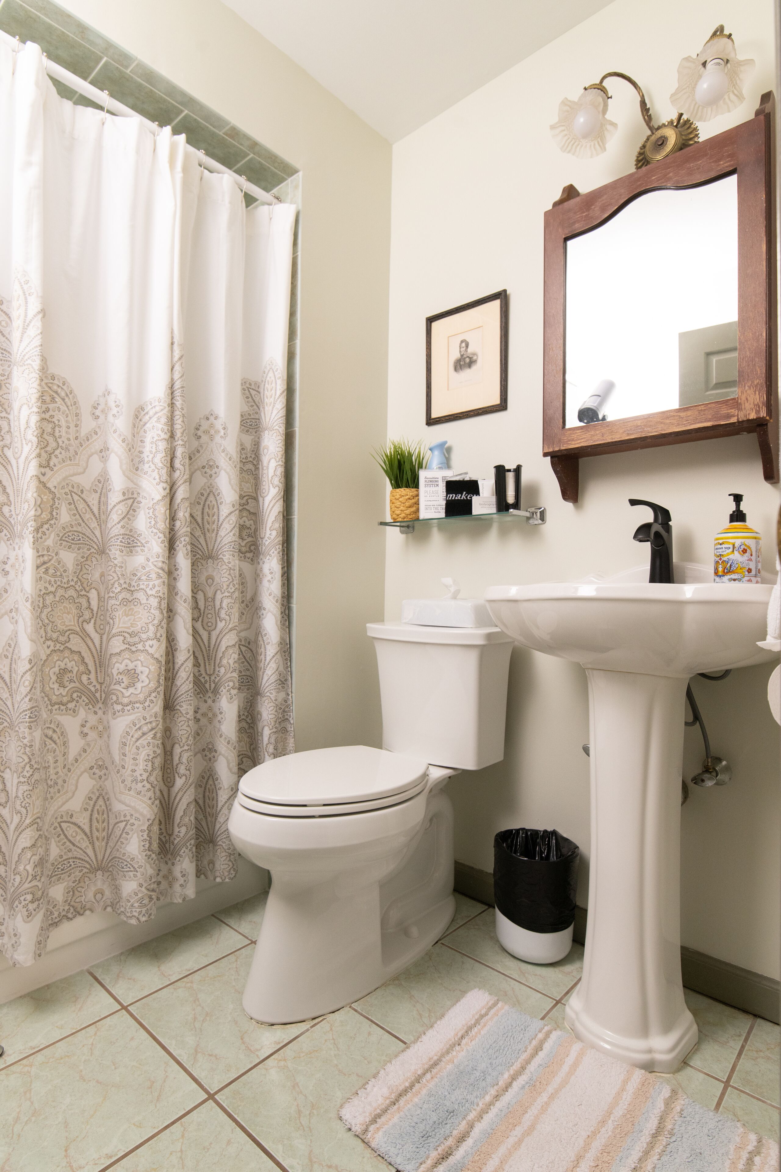 Un baño con inodoro, lavamanos y cortina de ducha.