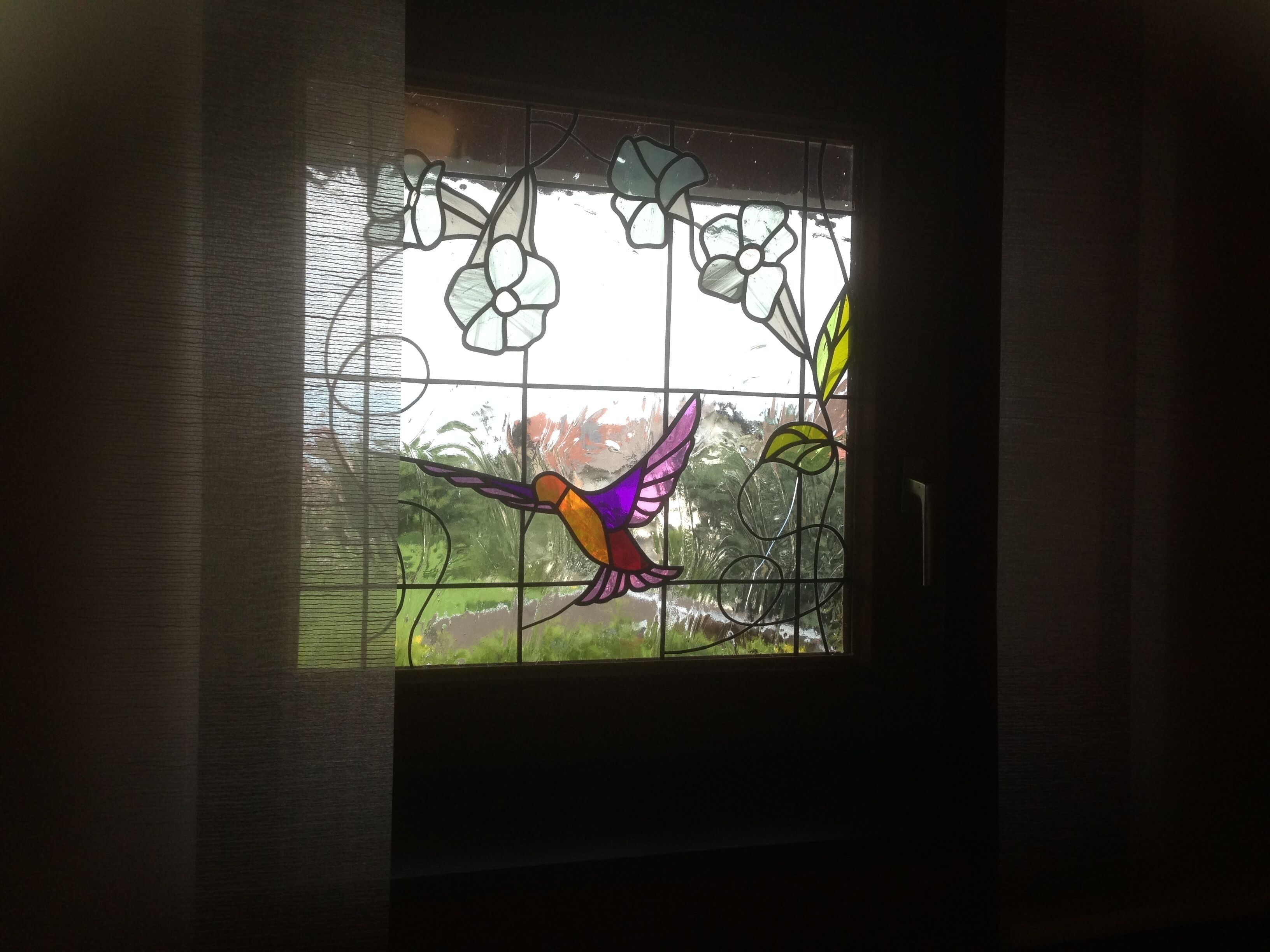 A stained glass window with a bird and floral design.