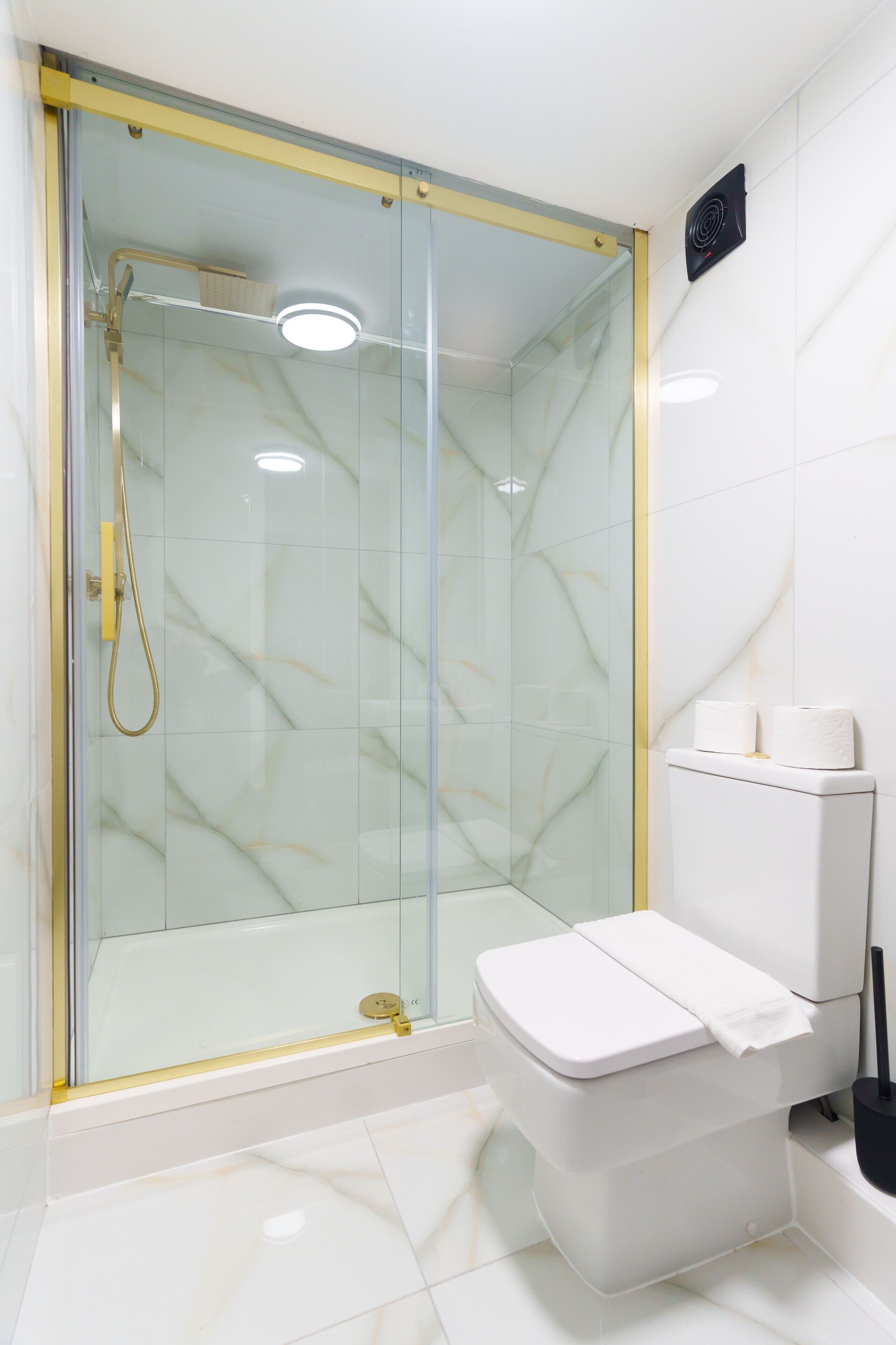 A modern bathroom with a glass-enclosed shower, a toilet, and a bidet.