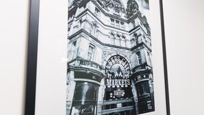 A framed black and white photograph of a building with a sign that reads "FARMERS MARKETS." - The Oasis Apartment (Leeds)