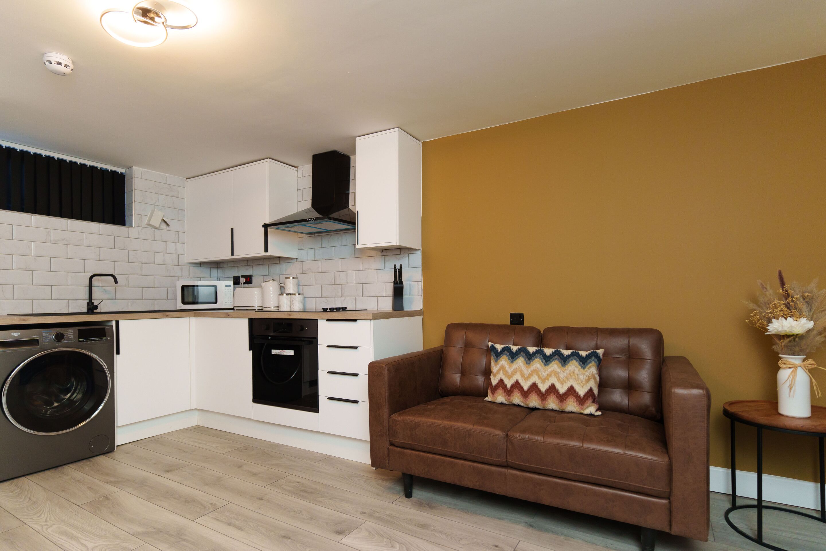 A compact kitchen with white cabinets, a microwave, and a washing machine.