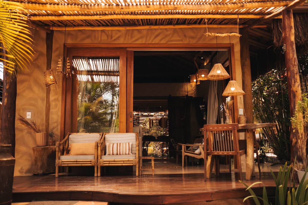 A wooden porch with a sofa and chairs, a table, and hanging lamps.