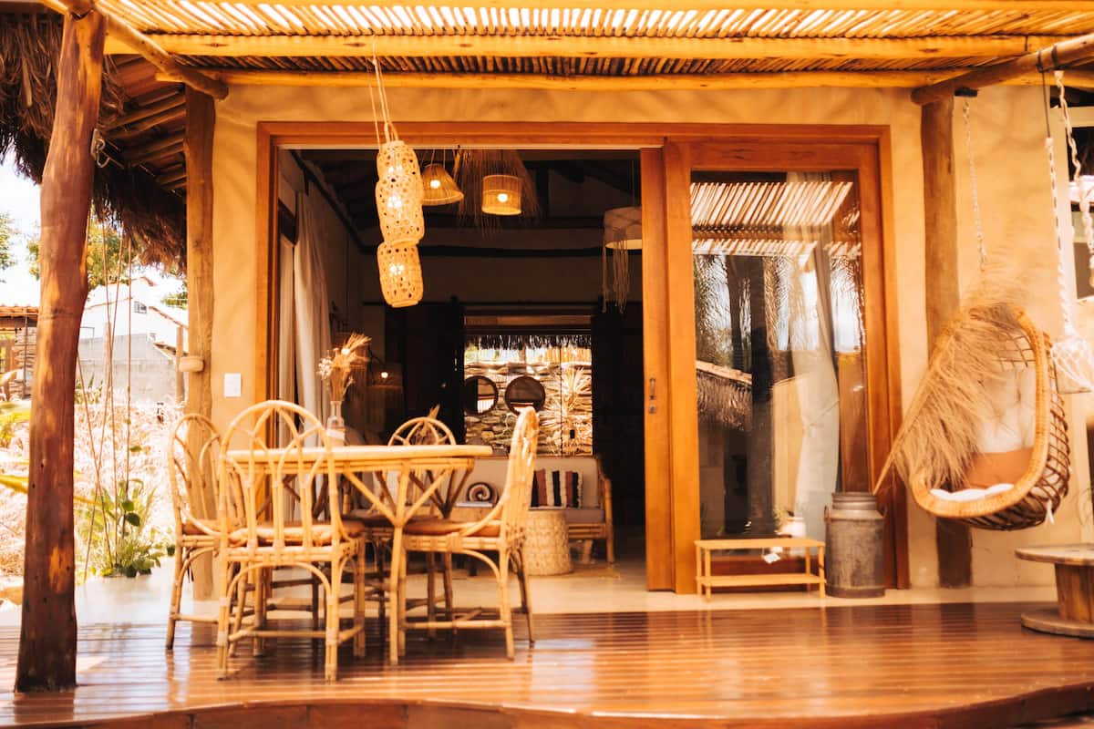 A wooden outdoor seating area with wicker furniture and hanging lights.