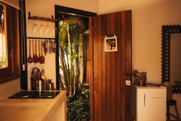 Een kleine keuken met houten kastjes, een inbouwfornuis en een compacte koelkast.