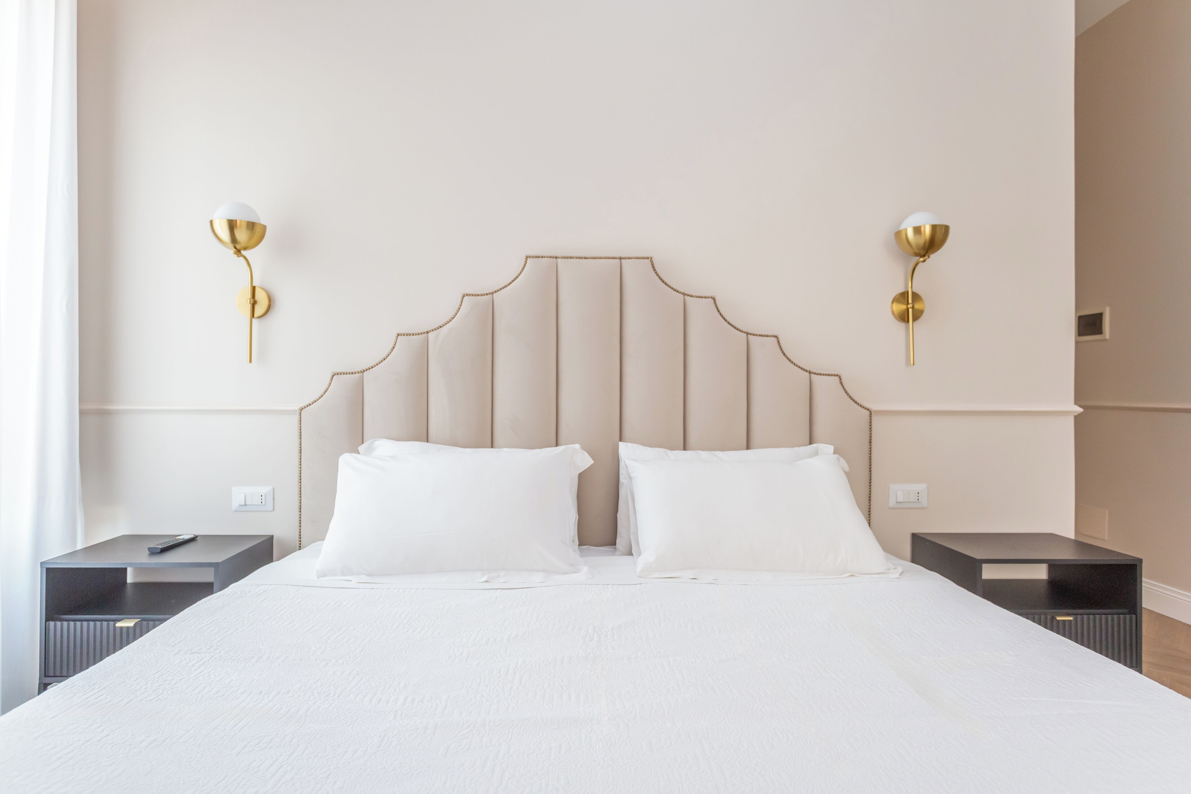 A hotel room with a large bed, two bedside tables, and two wall-mounted lamps.