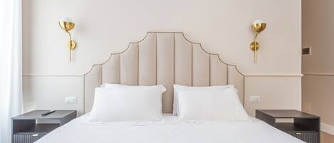 A hotel room with a large bed, two bedside tables, and two wall-mounted lamps.