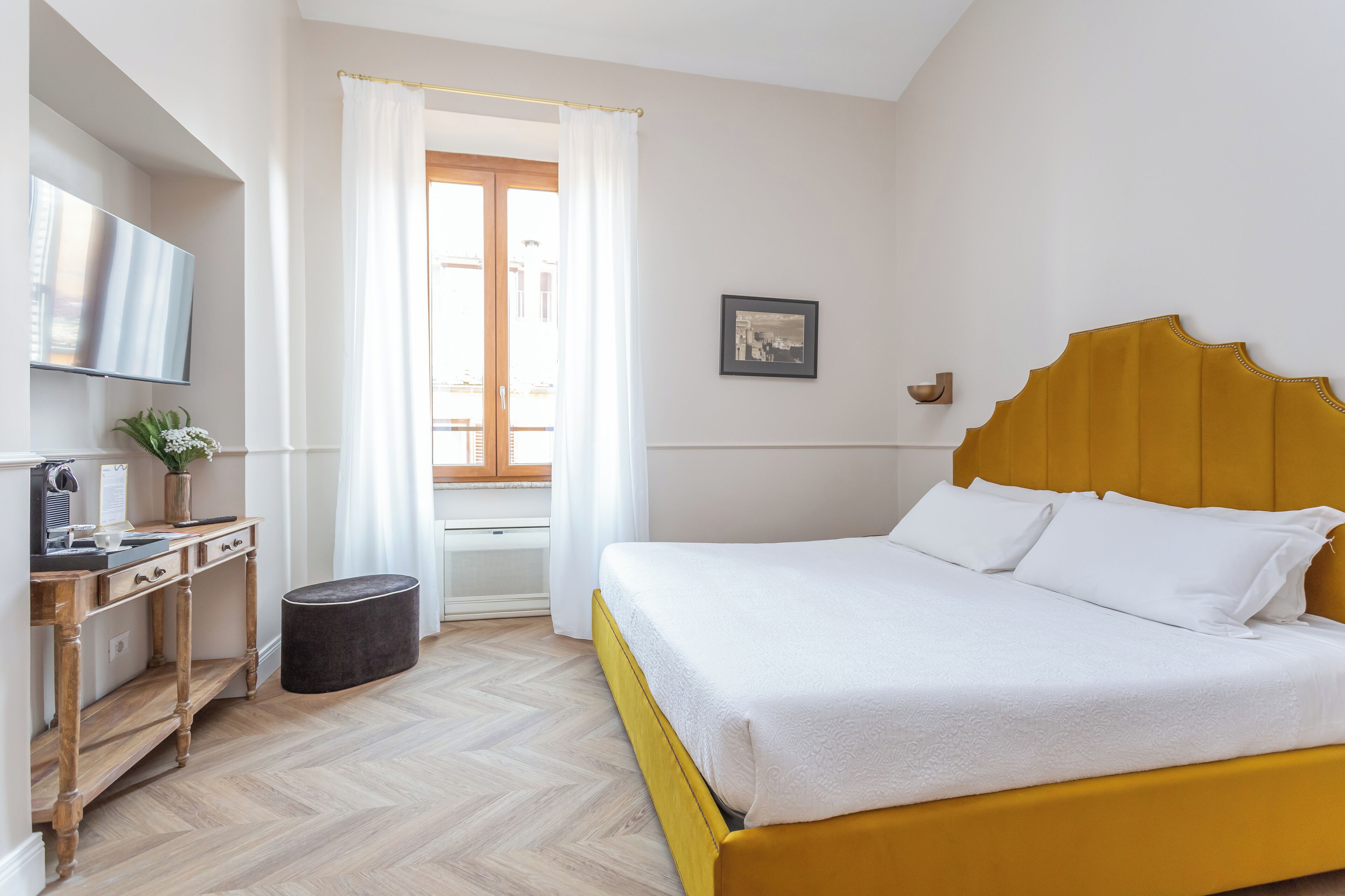 Ein Hotelzimmer mit Bett, Fernseher, Schreibtisch und einem Fenster mit Vorhängen.