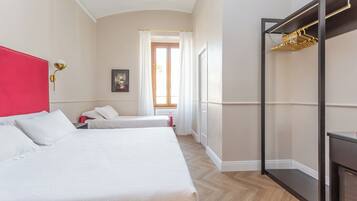 Ein Hotelzimmer mit zwei Betten, einem roten Kopfteil, einem Schrank mit Spiegel und einem Fenster mit Vorhängen.