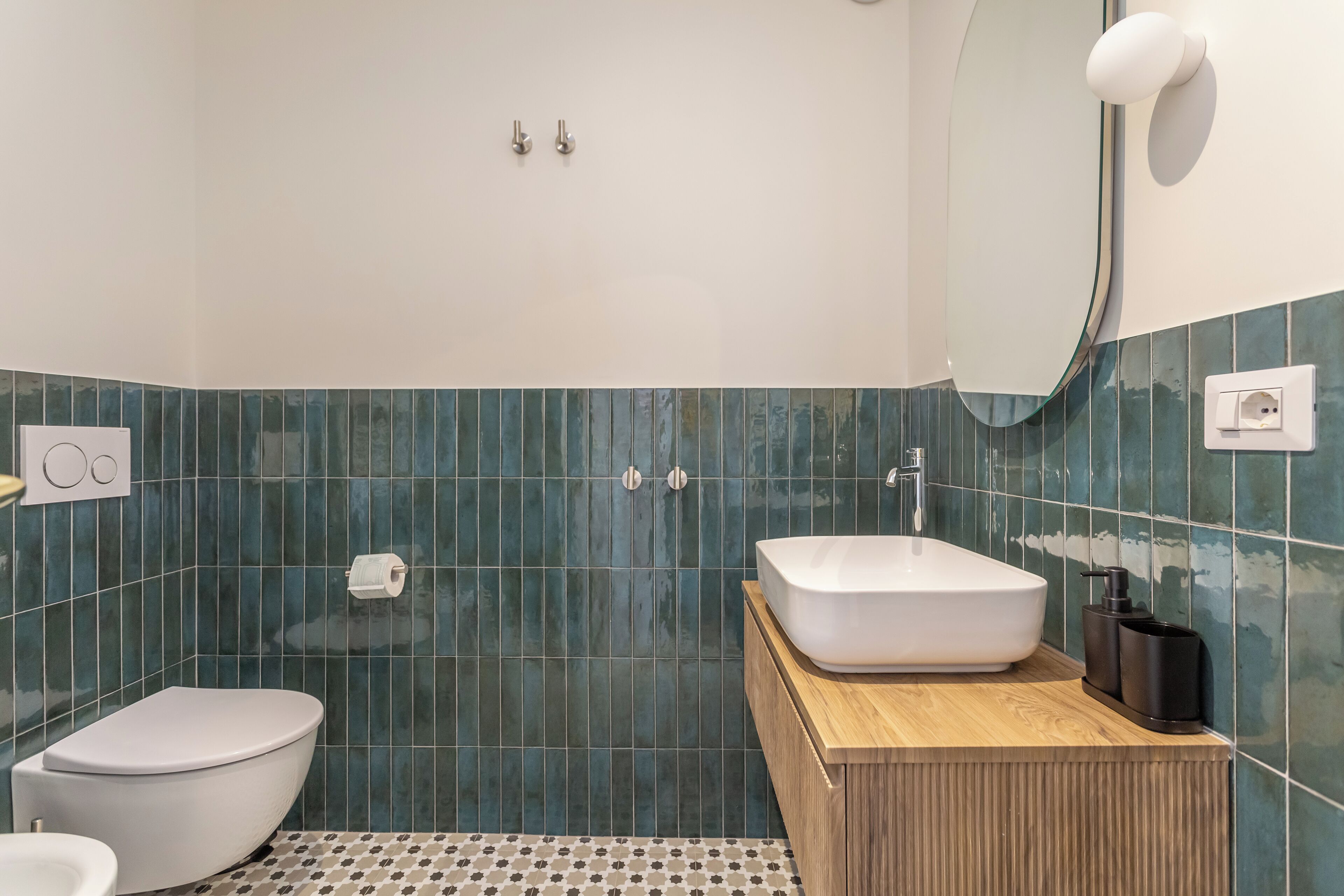 A modern bathroom with a white toilet, a freestanding sink, and a mirror above it.