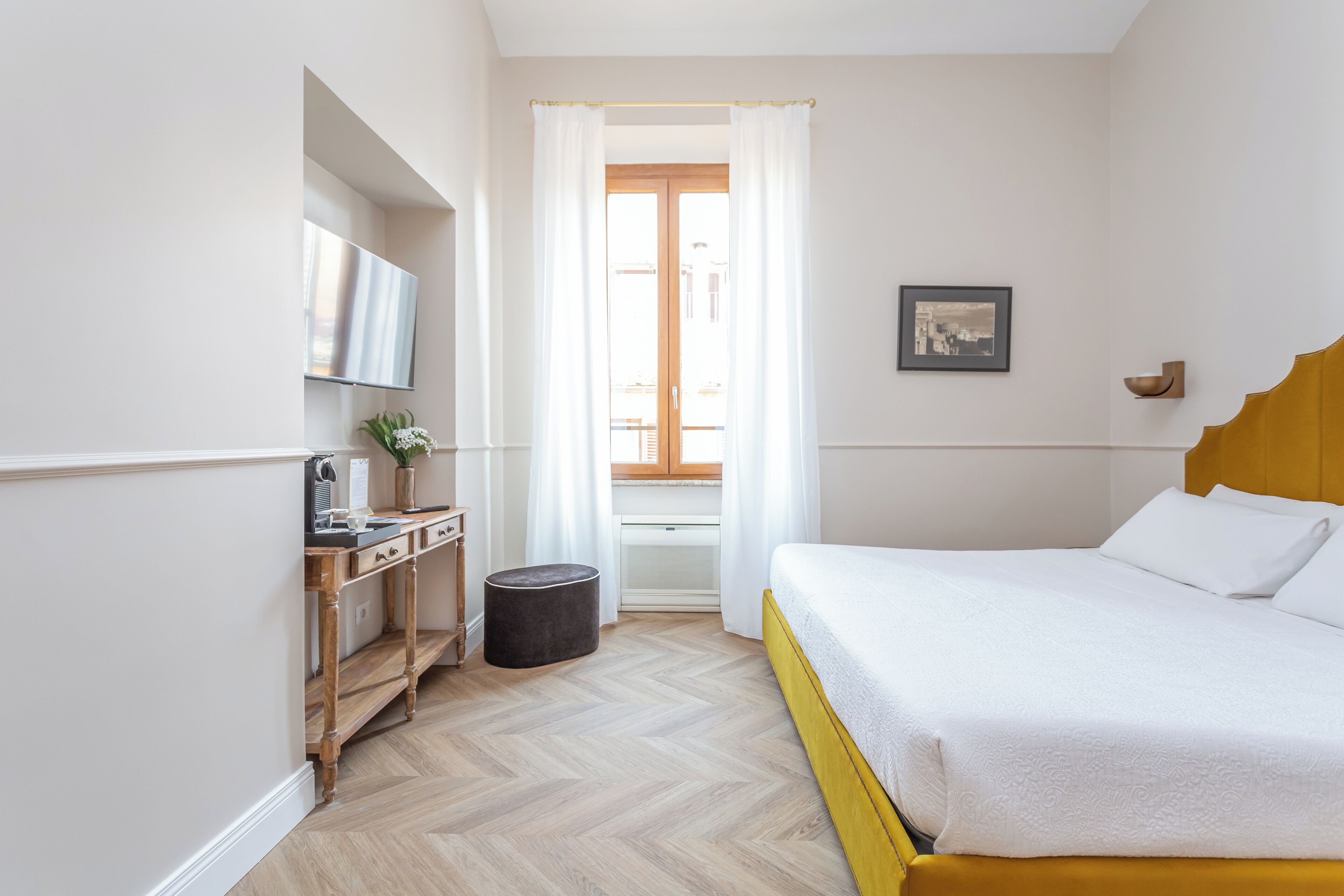 Una camera da letto con un letto, una scrivania, una sedia, una televisione e una finestra con tende.