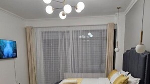 Ein modernes Schlafzimmer mit einem großen Bett, einem Fernseher an der Wand und einer Deckenleuchte.