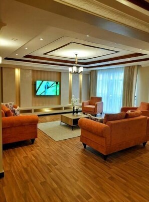 Relax in this inviting living room with a large flat-screen TV, comfortable sofas, and a central coffee table.
