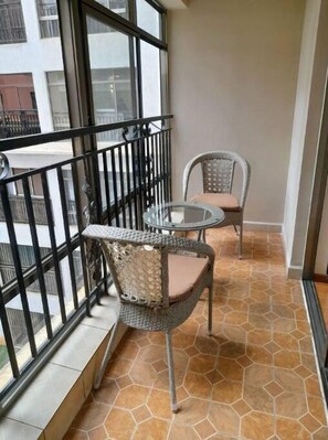 Enjoy the view from this balcony with a glass table and two wicker chairs.