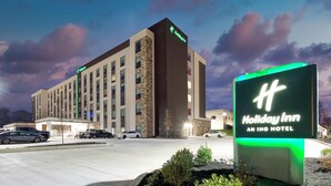 Ein Holiday Inn Hotel mit modernem Design, mit einem gut sichtbaren Schild und einem Parkplatz mit mehreren Autos.