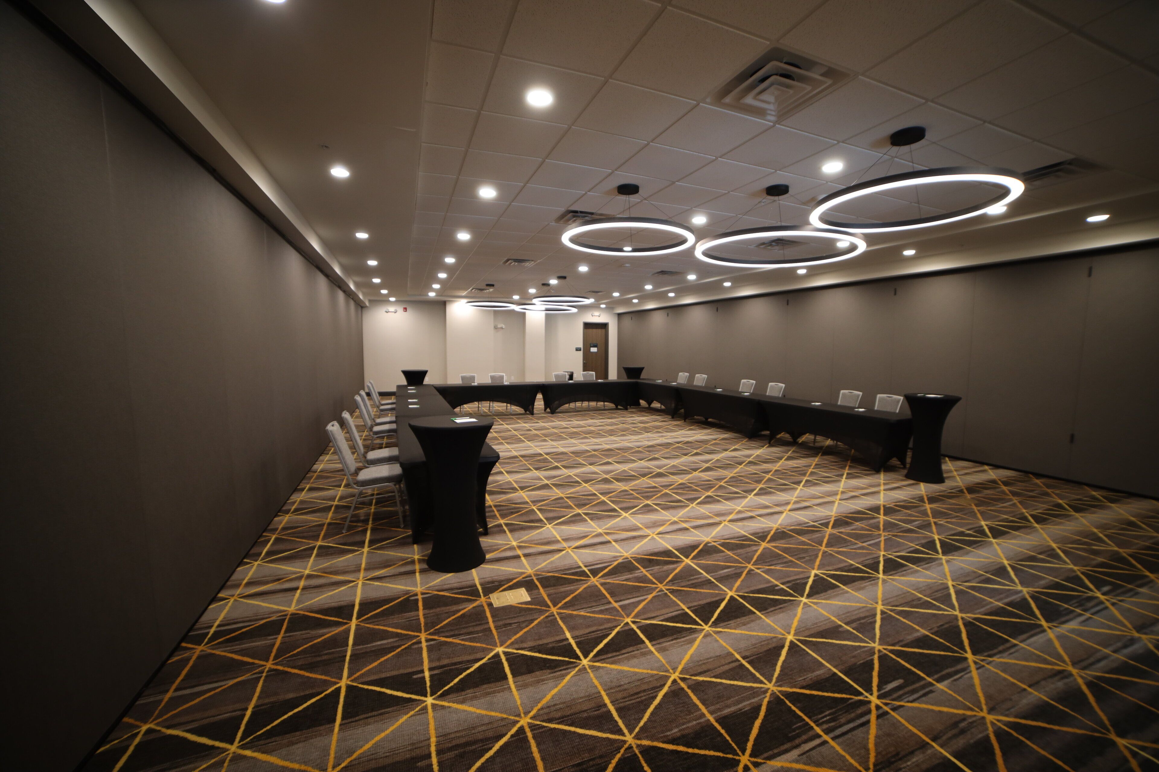 A conference room with a long table, chairs, and a patterned carpet.