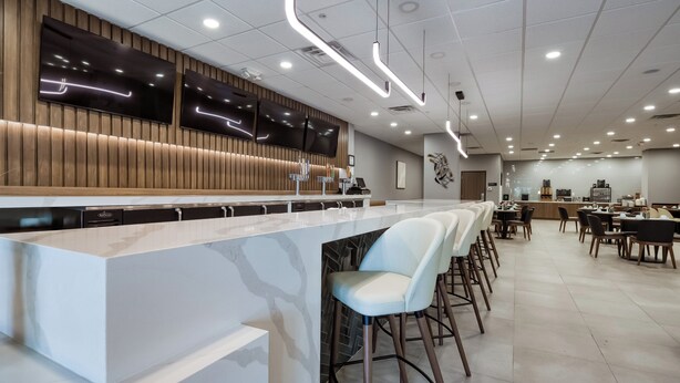 Eine moderne Bar mit einer langen Theke, Barhocker und einer Sitzecke mit Tischen und Stühlen.