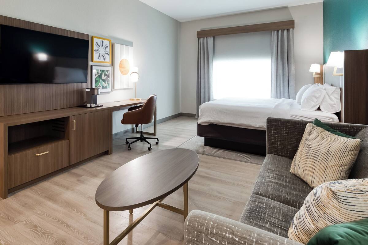 Ein Hotelzimmer mit Bett, Schreibtisch, Fernseher und einer Sitzecke.