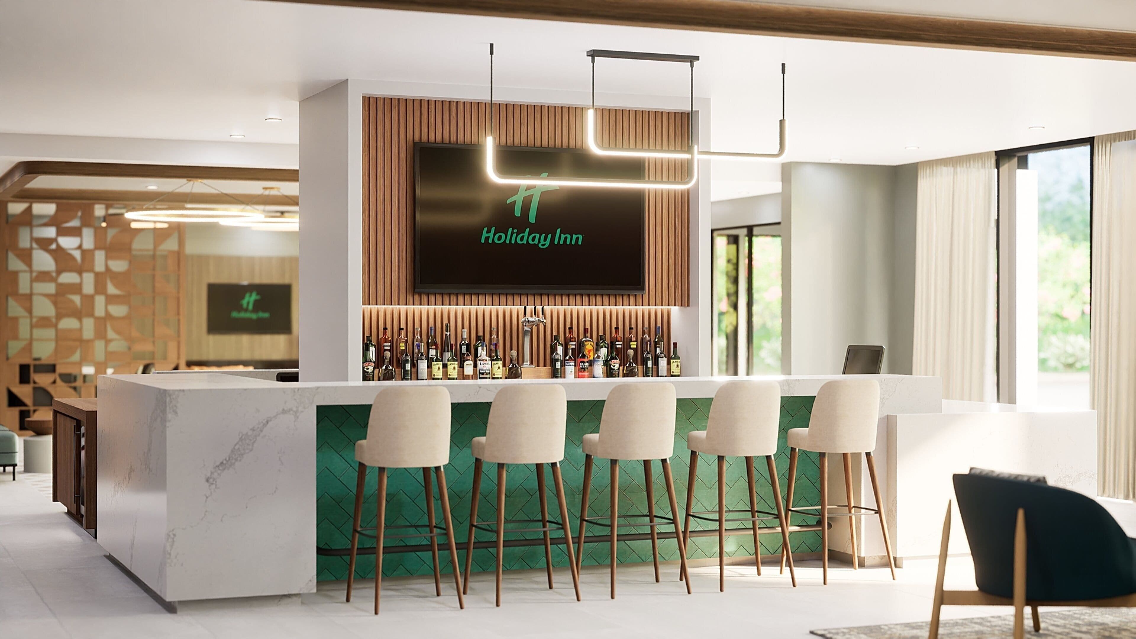 A bar area with a modern design, including a marble countertop, bar stools, and a variety of liquor bottles.