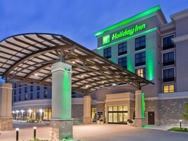 Un hotel Holiday Inn con entrada cubierta y un letrero verde llamativo.