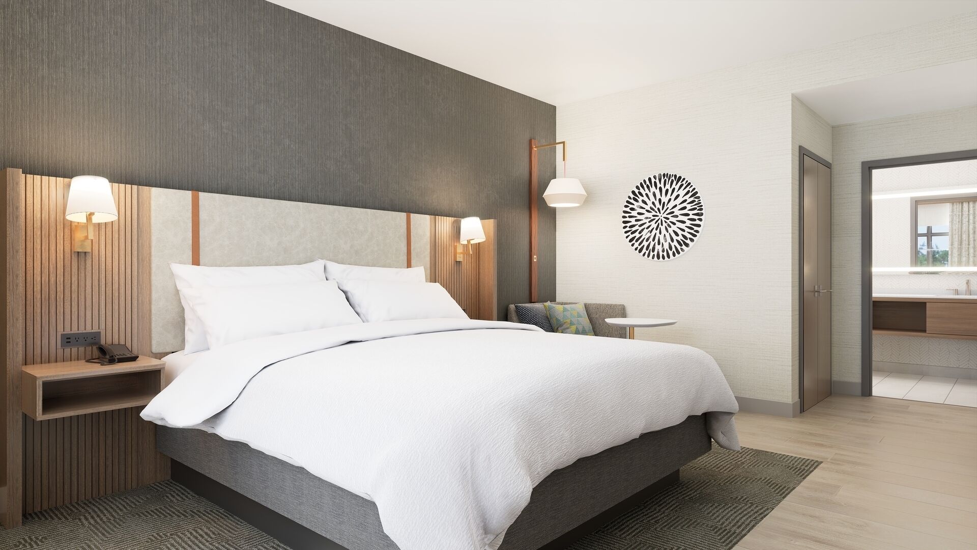 Een moderne hotelkamer met een groot bed, bedlampen, een klein tafeltje en een badkamer die zichtbaar is door een open deur.