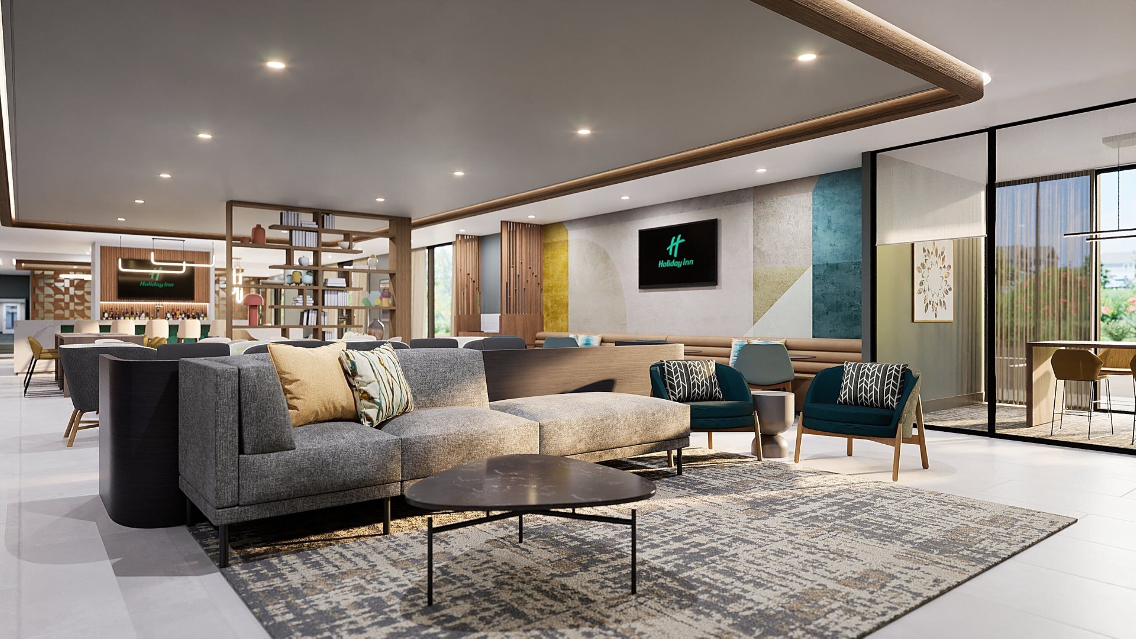 A modern hotel lobby with a sofa, chairs, a coffee table, and a reception desk.