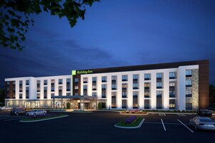 Un hotel Holiday Inn con un diseño moderno, que cuenta con un estacionamiento amplio y una entrada bien iluminada.