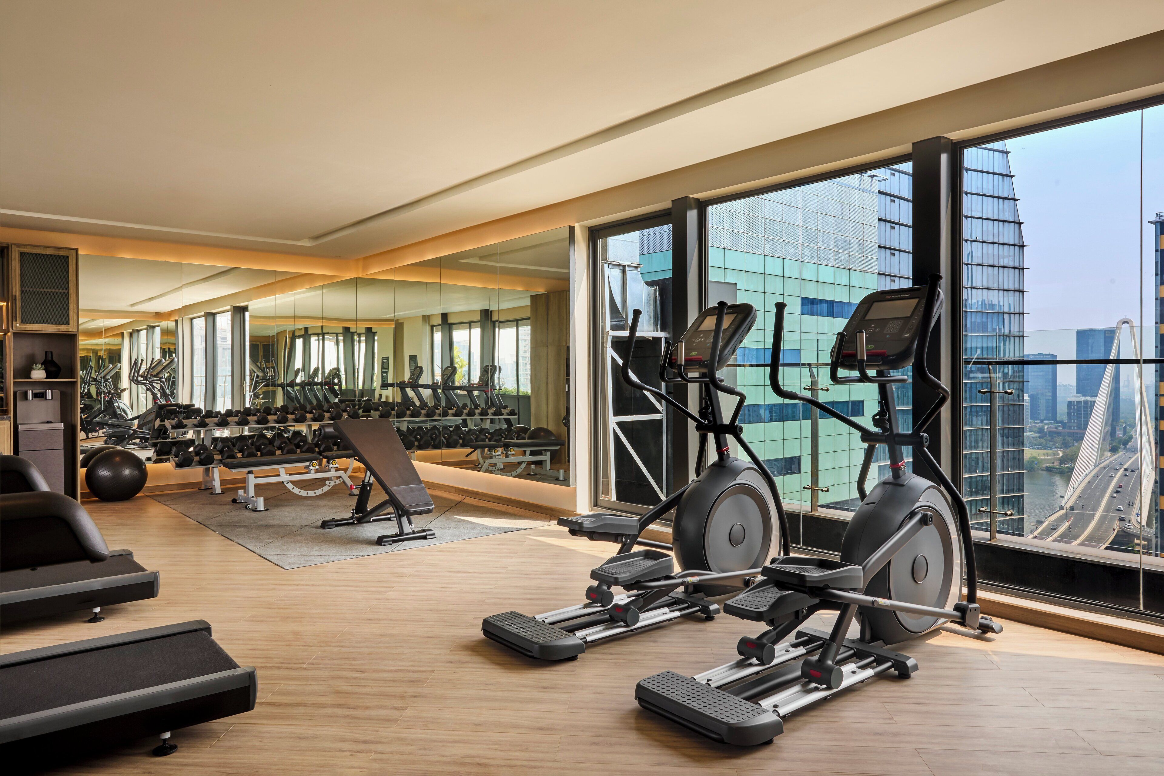 A modern gym with treadmills, elliptical machines, and free weights.