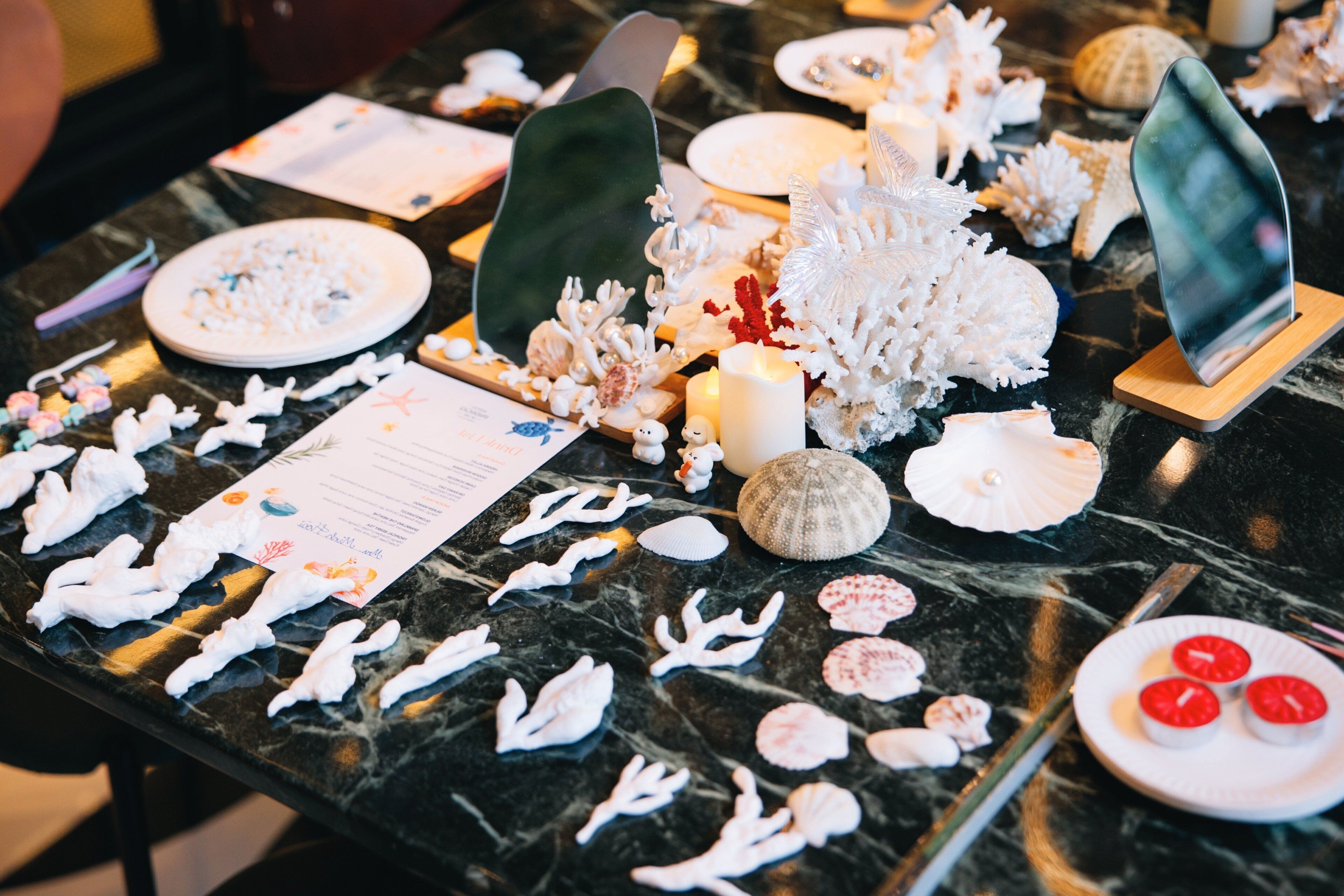 A table with various decorative items including seashells, coral, and paper cutouts.