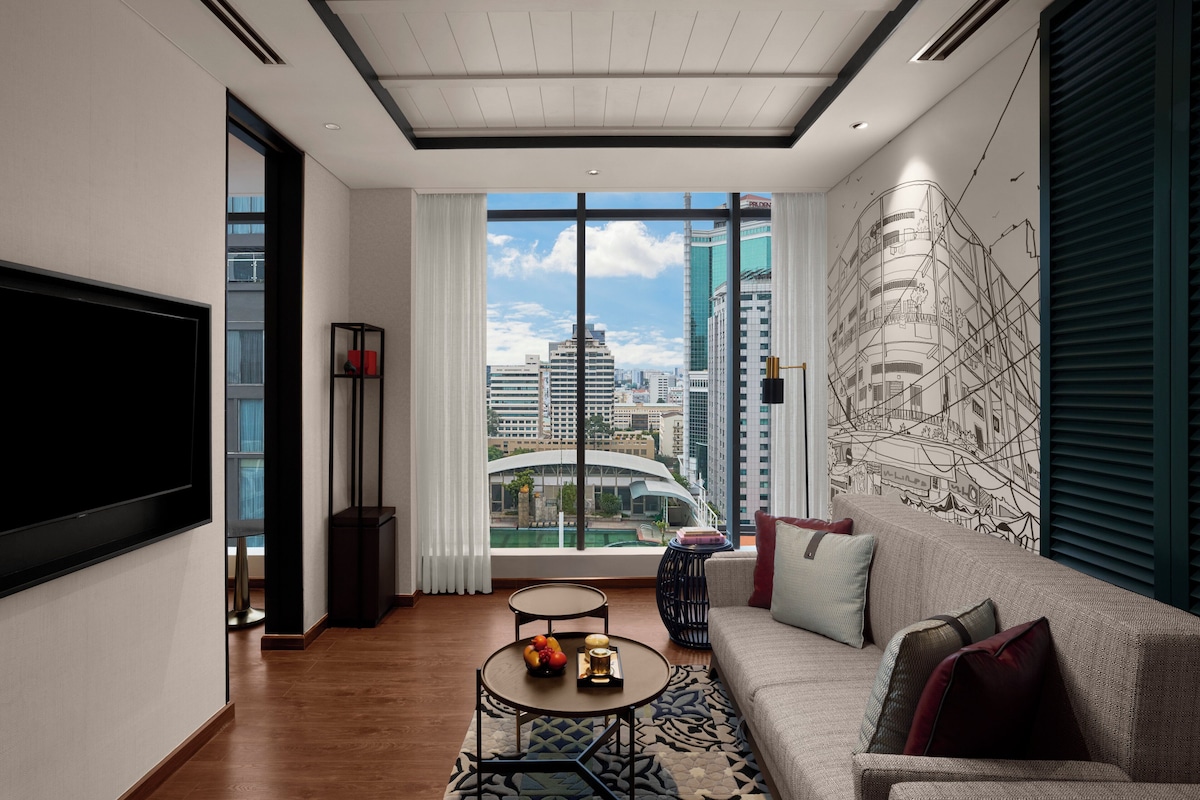 A modern living room with a large window, a flat-screen TV, a sofa, a coffee table, and a decorative wall mural.